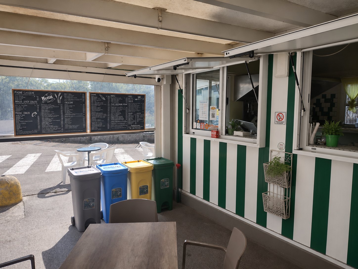 La zona coperta di Piadinamente con bancone, tavoli e lavagne del menu
